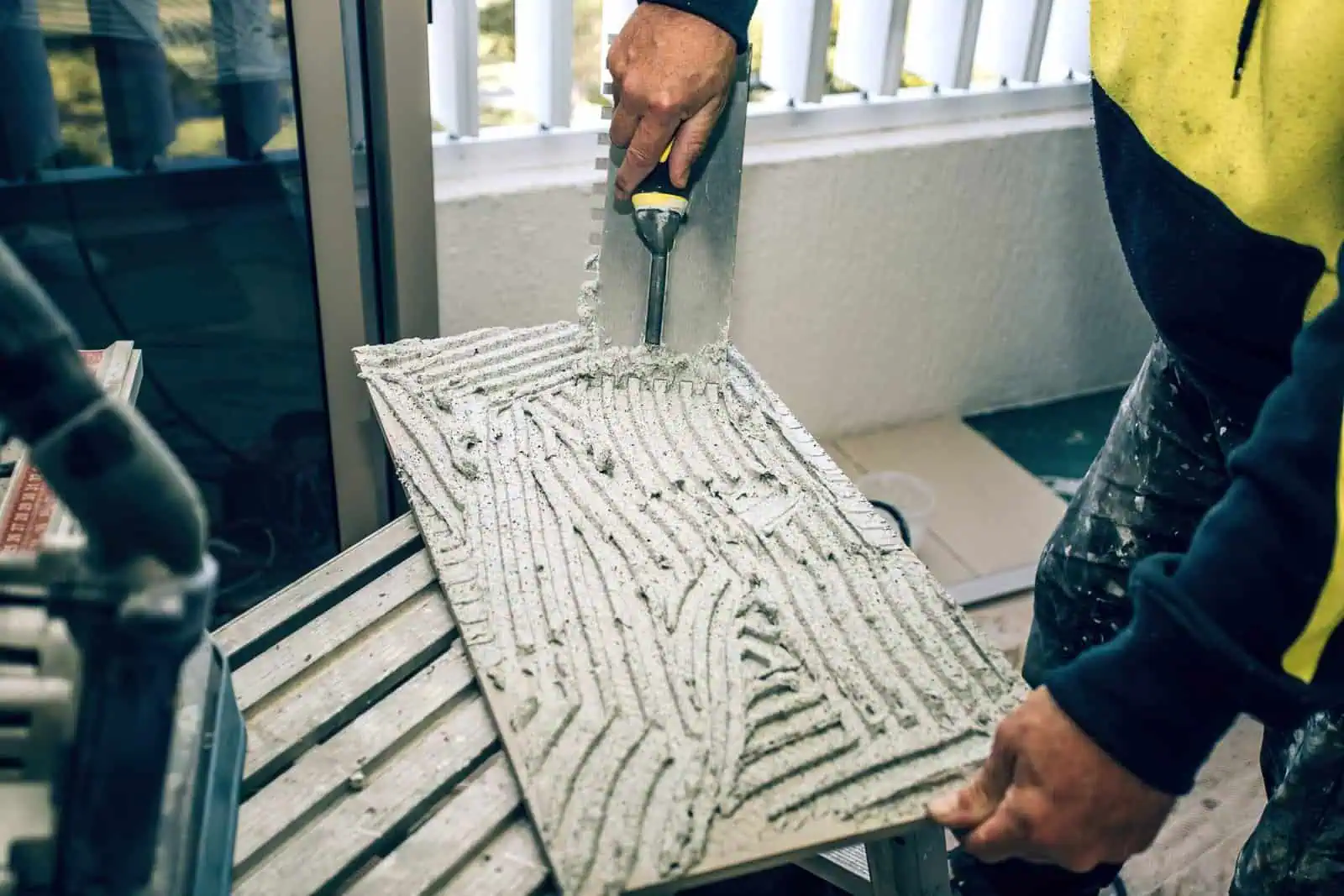 Detailed view of tile being installed on a balcony with adhesive for durable flooring.